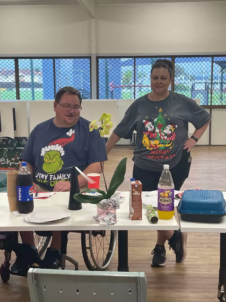 A participant and Heidi in Christmas T-shirts at a shared lunch table